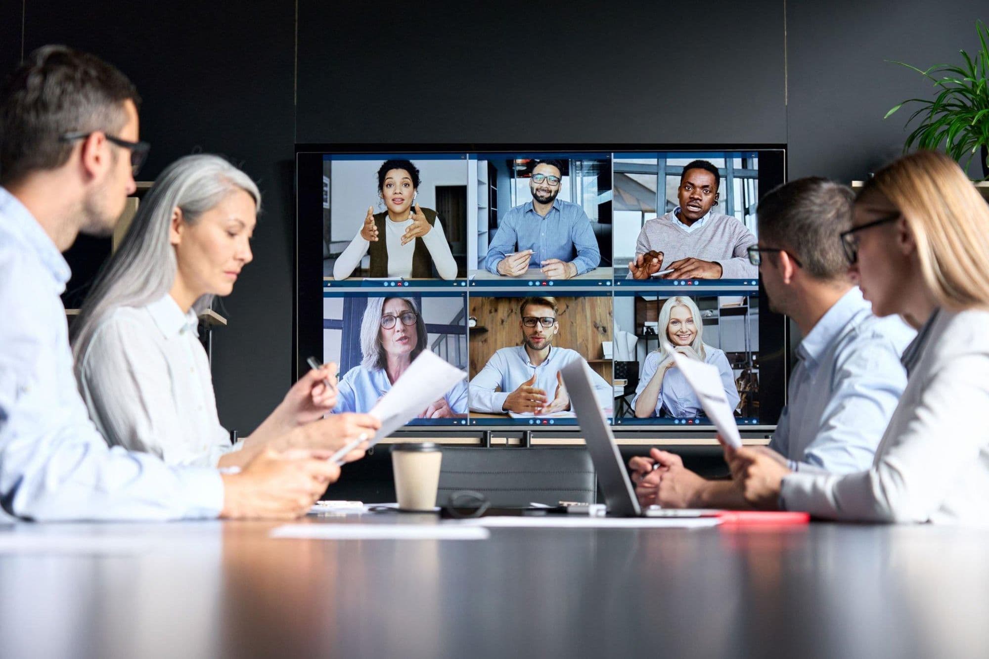 A team in a meeting room talking with colleagues on a video call