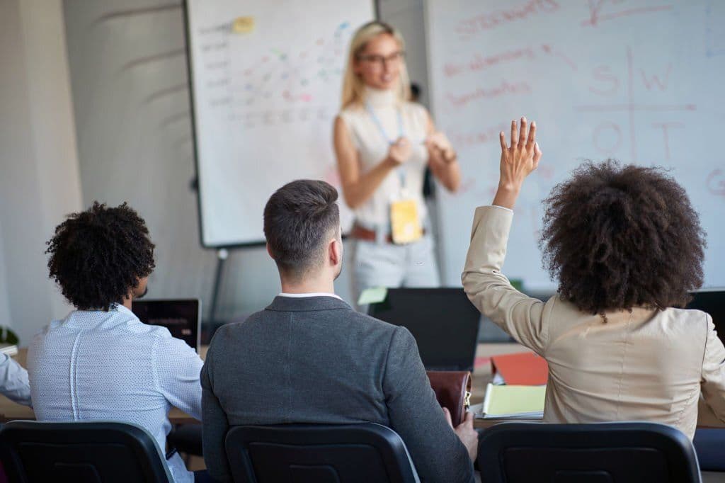 A facilitator leading a training session while participants raise their hands